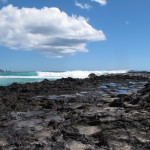 Volcanic rock at the cove receives the incoming waves