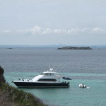 Yachts moor in a Rottnest Island cove with Perth in the background