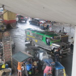 Jeepneys and tuk-tuks throng under the cement train tracks