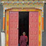 A monk stops to pray at the temple door, Thak Thog Monastery